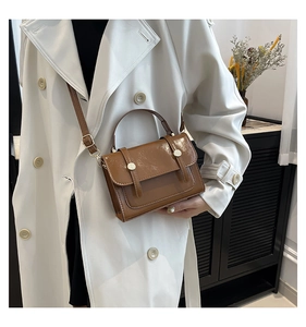 Braune Lackleder-Handtasche mit Metallschnalle kombiniert mit beigefarbenem Trenchcoat