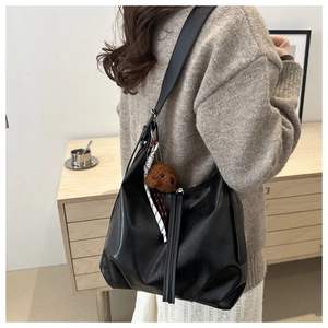 Détail du sac cabas en cuir noir avec breloque chien en peluche et large bandoulière