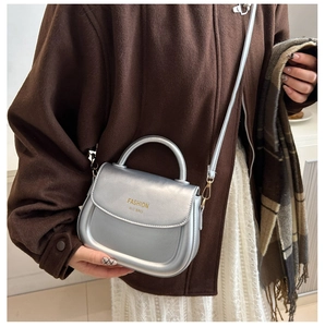 Detail of silver metallic crossbody bag with fashion logo and adjustable shoulder strap