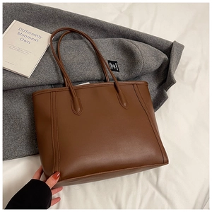 Close-up of brown faux leather tote bag on grey coat with a vintage lifestyle aesthetic