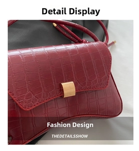 Detail of dark red crocodile embossed shoulder bag with elegant gold metal buckle