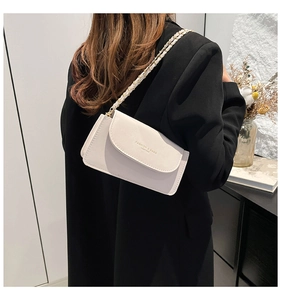 Détail d'un sac à rabat crème élégant avec une bandoulière chaîne dorée et cuir texturé