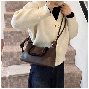 Detail of dark brown leather crossbody bag with pleated edges and knotted strap