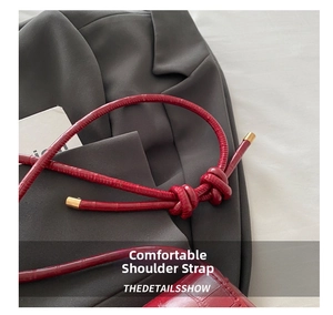 Detail view of the red crocodile pattern strap with elegant knot and golden hardware