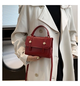 Rote Vintage Umhängetasche mit goldener Schnalle an Model im beigen Trenchcoat getragen