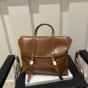 Vintage brown leather tote bag with flap closure and top handle on a chair