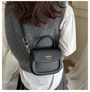 Side view of woman carrying a black matte saddle bag with gold lettering decoration