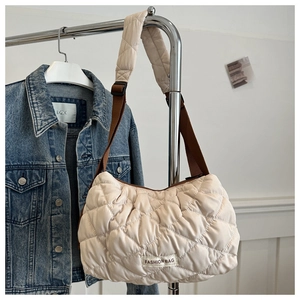 Close-up of beige quilted tote bag with fashion label and brown adjustable strap