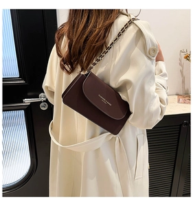 Détail du sac à rabat marron avec inscription dorée et bandoulière en chaîne