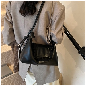 Detail of black pleated crossbody bag with ruffle flap and stylish knotted shoulder strap