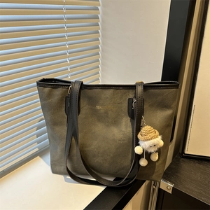 Olive green tote bag with black leather handles and cute sheep pendant on window sill