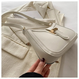 Detail of off-white leather shoulder bag with gold metal clasp and premium stitching