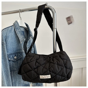 Detail of quilted black puffer bag featuring a fashion woven label and adjustable strap