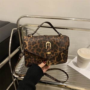 Chic leopard print crossbody bag with gold buckle on a stylish indoor display