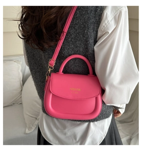 Detail of hot pink leather bag featuring gold buckles and adjustable shoulder strap