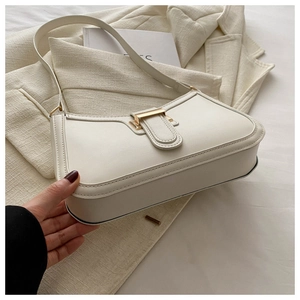 Detail of elegant cream leather shoulder bag with a polished golden rectangular clasp