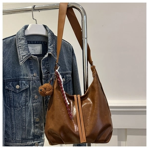 Détail du sac hobo marron avec breloque ours et large bandoulière sur denim