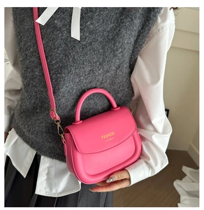 Close-up of a stylish hot pink saddle bag with gold lettering and adjustable crossbody strap