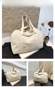 Detailed close-up of a white nylon travel tote bag with front zipper pocket and light texture