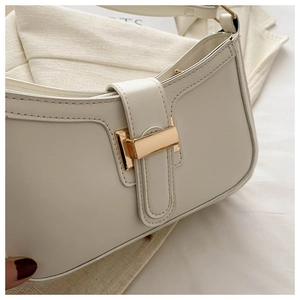 Close-up of beige faux leather handbag with a polished gold-tone rectangular metal lock