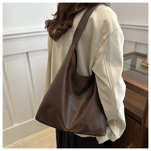 Detail of dark brown leather tote bag showing soft texture and wide shoulder strap