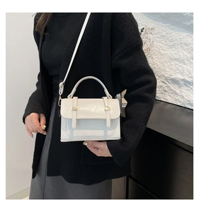 Close-up of cream vintage satchel showing glossy leather and golden metal buckle details