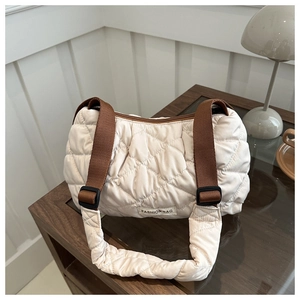 Close-up of quilted cream tote bag with diamond stitching and dark brown shoulder strap