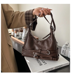 Detail of vintage brown PU leather bag with decorative belt strap and metallic buckle