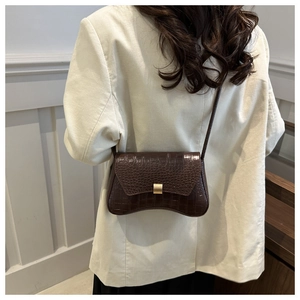 Detail of vintage crocodile pattern baguette bag with gold buckle on a beige blazer