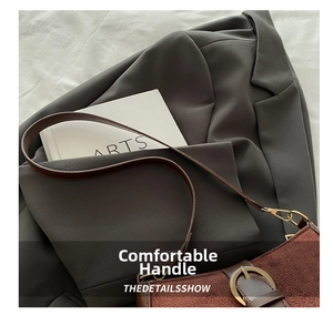 Detail of vintage gold metal buckle on brown suede crossbody bag with soft leather strap