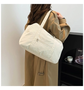 Detail of off-white nylon tote bag with pleated texture worn over a khaki trench coat