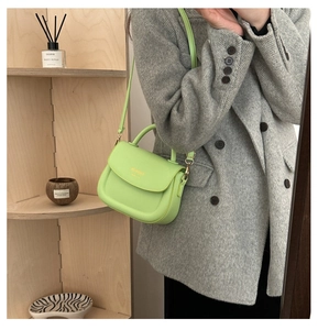 Close-up of lime green leather handbag featuring gold logo and metallic hardware