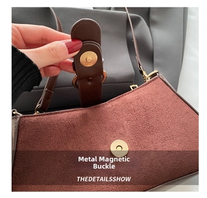 Close-up of golden magnetic snap button on brown suede bag with textured finish