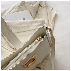 Detail view of cream leather shoulder bag with gold zipper and stylish metal buckle