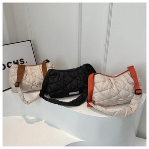Detailed view of quilted puffer shoulder bags in various colors on display