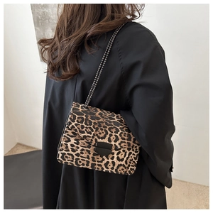 Detail of trendy leopard print shoulder bag featuring black metal geometric clasp and chain strap