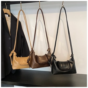 Close-up of three half-moon bags in khaki, brown, and black with ruffled flap detail