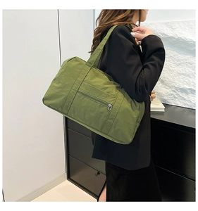 Side view of a grass green nylon travel bag worn by a model in a modern setting