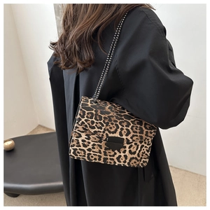 Detail of leopard print shoulder bag with black chain strap and metal buckle on a model