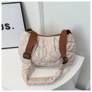 Macro detail of beige quilted puffer tote bag with brown adjustable strap and logo