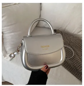 Detailed macro view of silver saddle bag with metallic texture and golden hook hardware