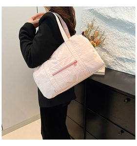 Pink waterproof nylon gym bag shown on shoulder with practical zipper front pocket