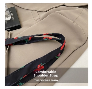 Detail showing high-quality black nylon shoulder strap with red strawberry prints on suit