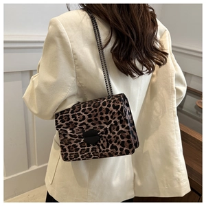 Detail shot of leopard print crossbody bag with metal buckle and chain strap on model