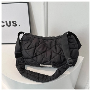 Macro detail of black quilted shoulder bag featuring wide strap and fashion logo tag