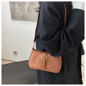 Detail of retro golden brown suede underarm bag featuring a metallic belt buckle strap