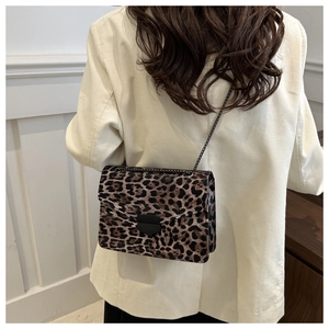 Detail of leopard print crossbody bag featuring a black metal clasp and chain strap