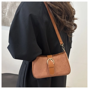 Detail of vintage brown shoulder bag showing suede patchwork and golden buckle on model