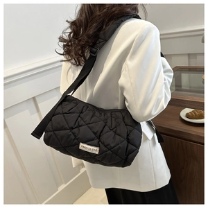 Detail of black quilted puffer bag with adjustable wide strap and fashion label detail