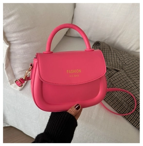 Detail of hot pink leather mini saddle bag with gold hardware and fashion logo